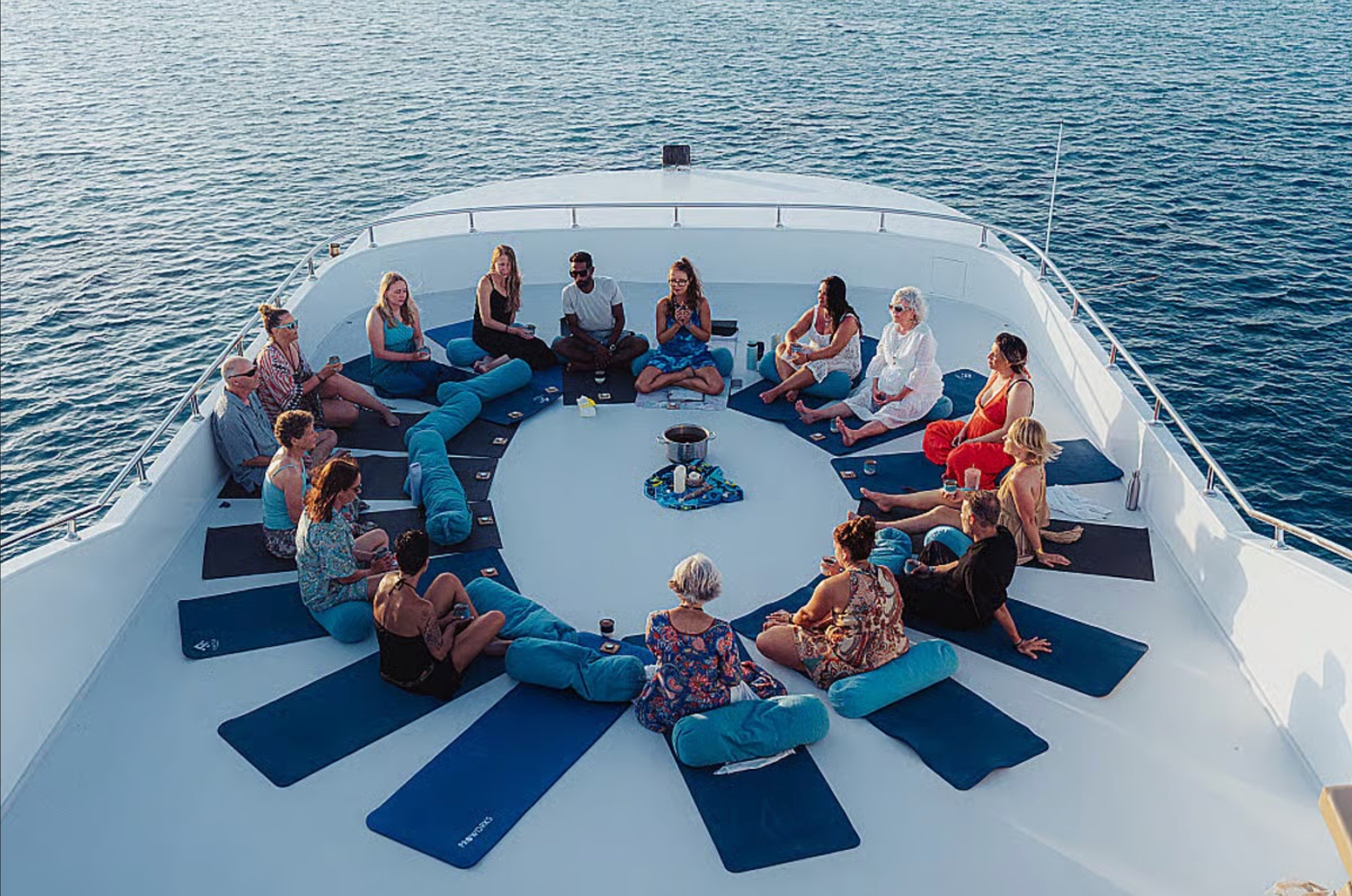 Overhead view of a group breathwork session on the boat's deck at sea.